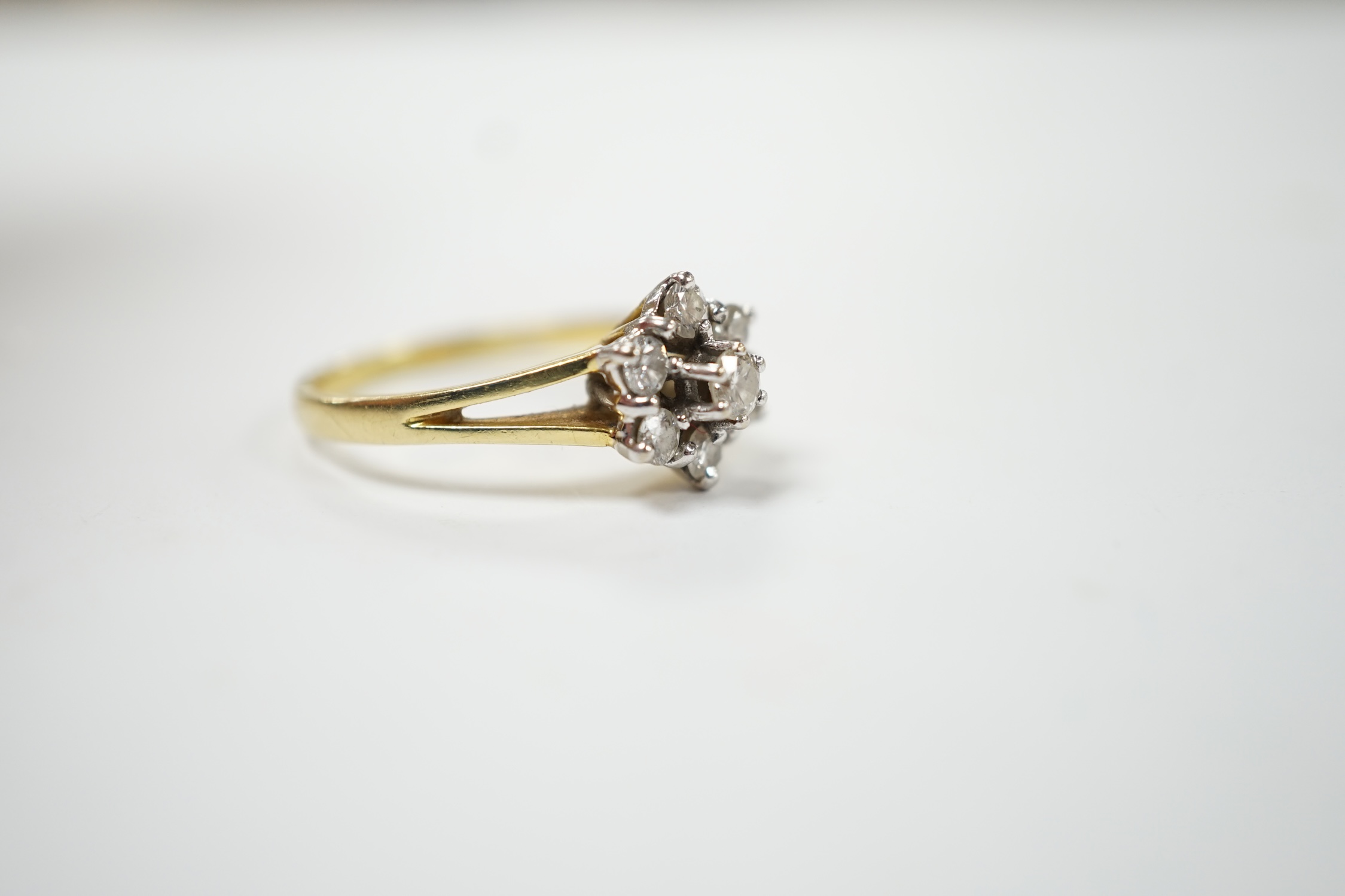 A modern 18ct gold and seven stone diamond set flower head cluster ring, size M, gross weight 3.2 grams. Fair condition.